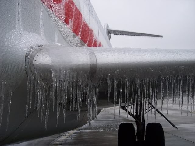 Icicles hanging from an airplane wing outside.