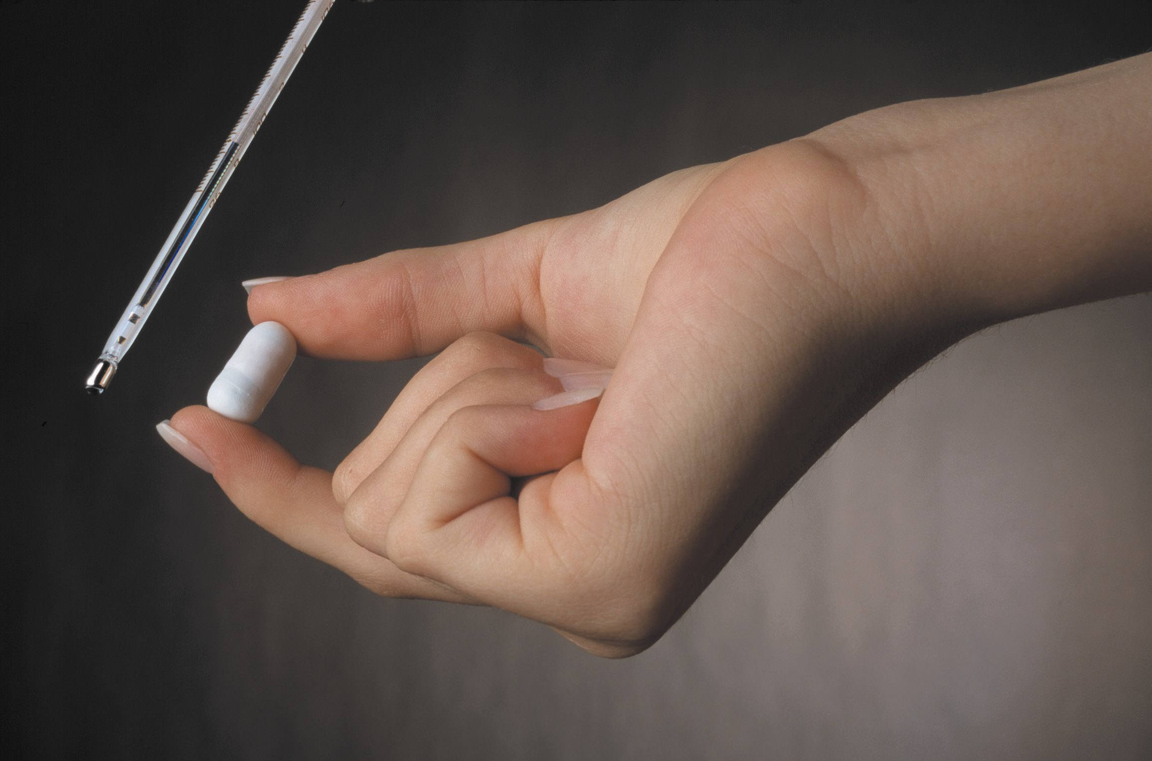 Hand holding an ingestible thermometer pill 