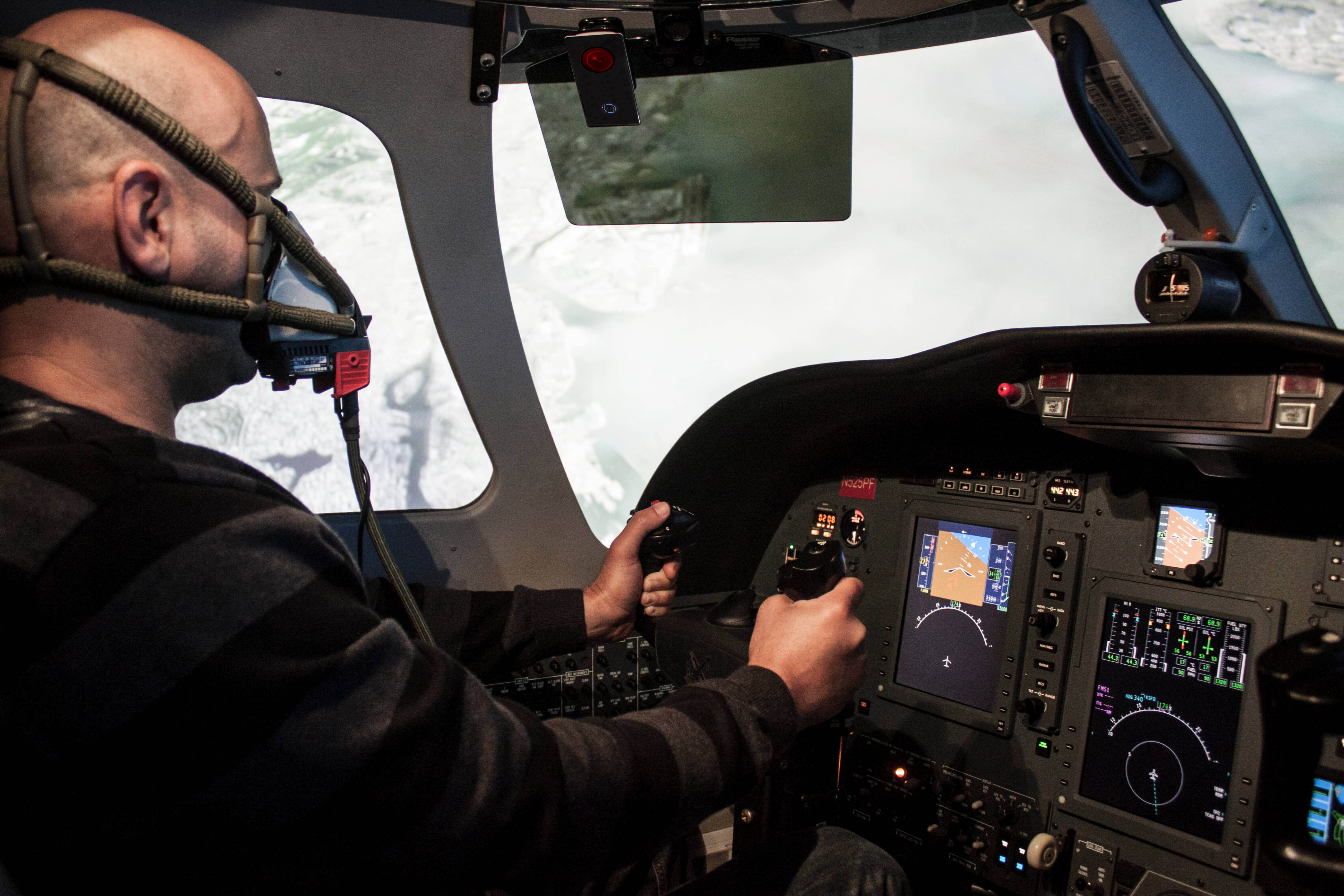 A pilot flying a plane with their handheld oxygen monitor overhead.