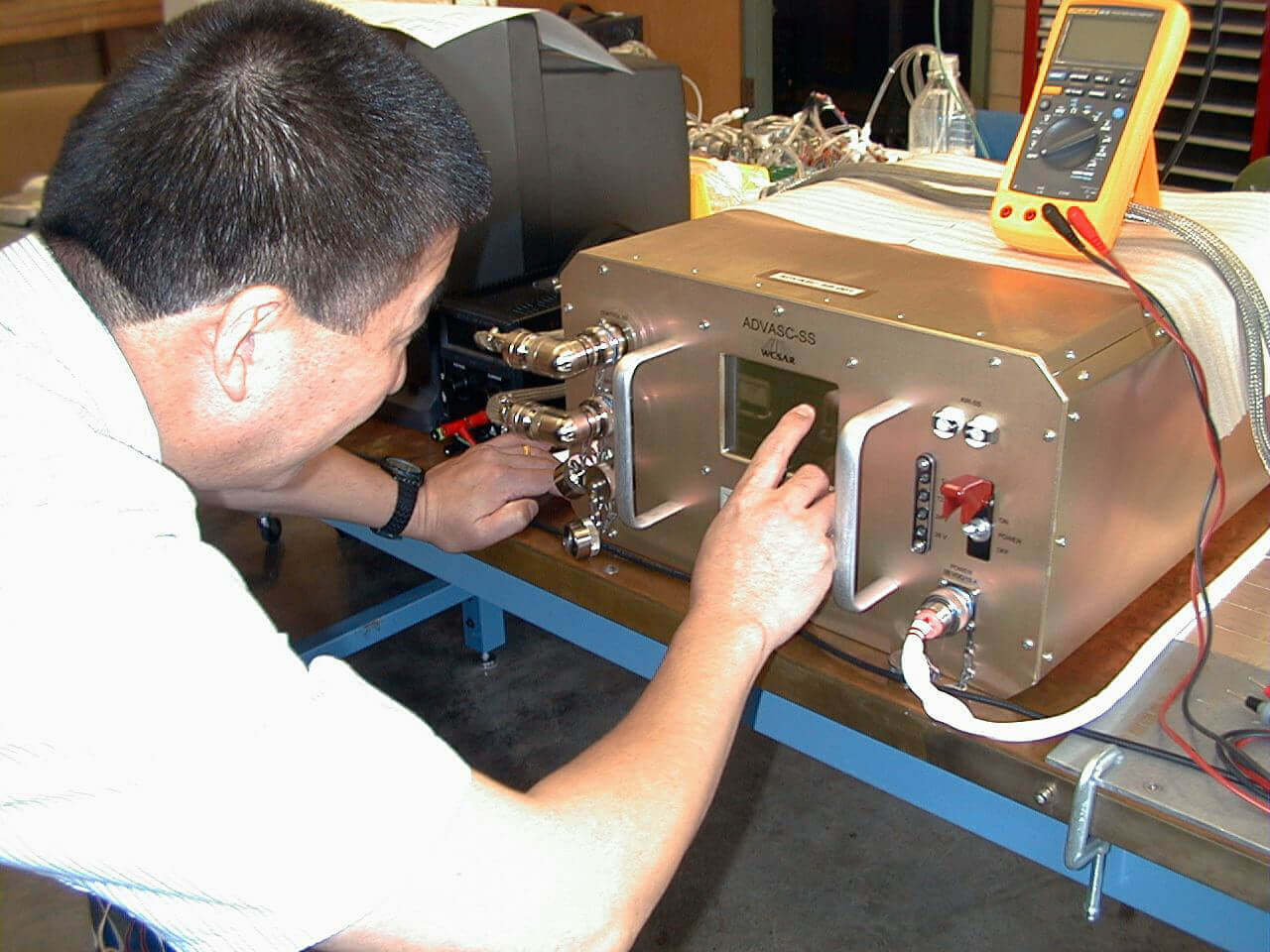A researcher inspecting a plant growth unit designed for operation in space