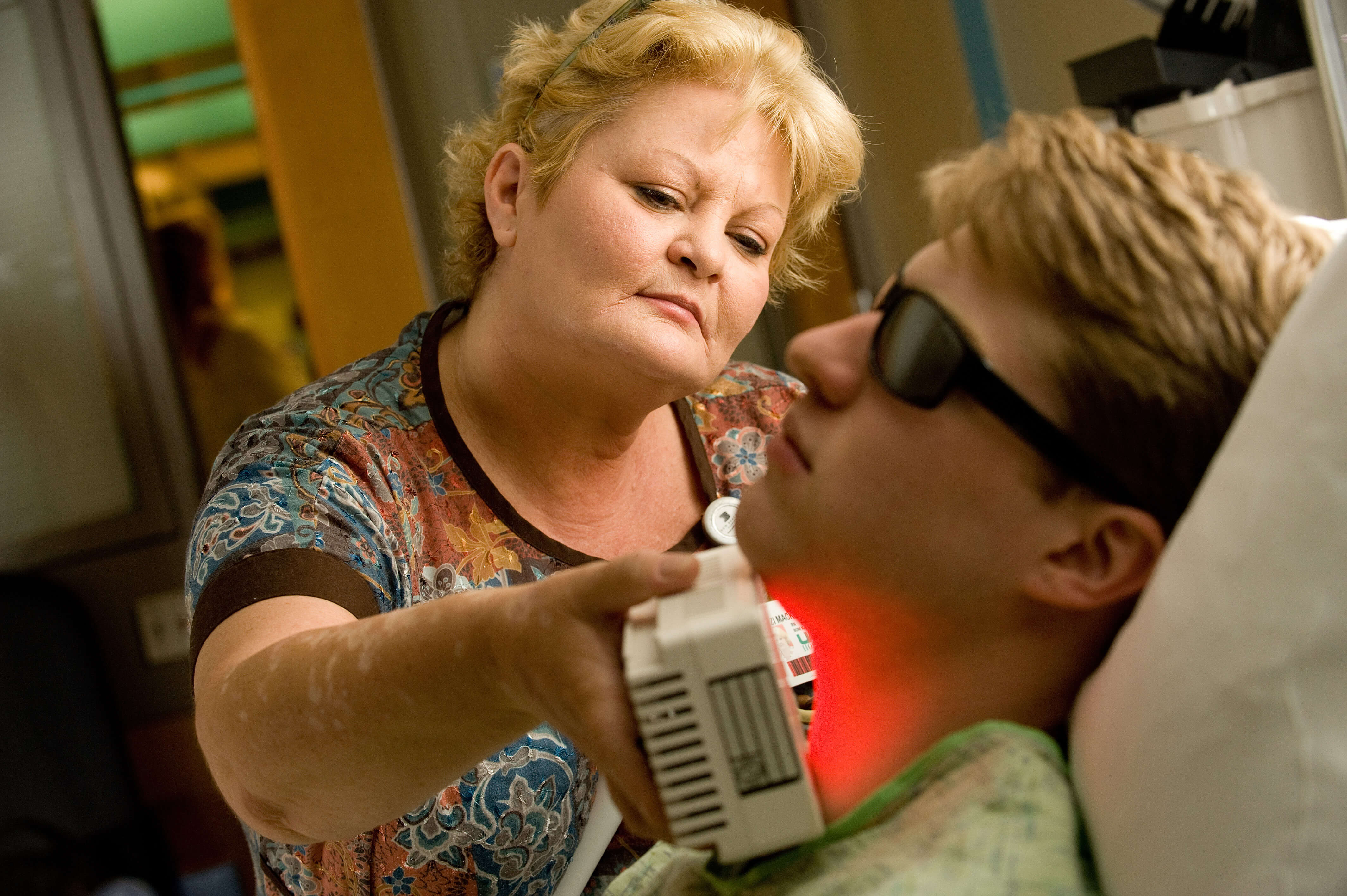 A therapist uses a red-light therapy device on a patient 