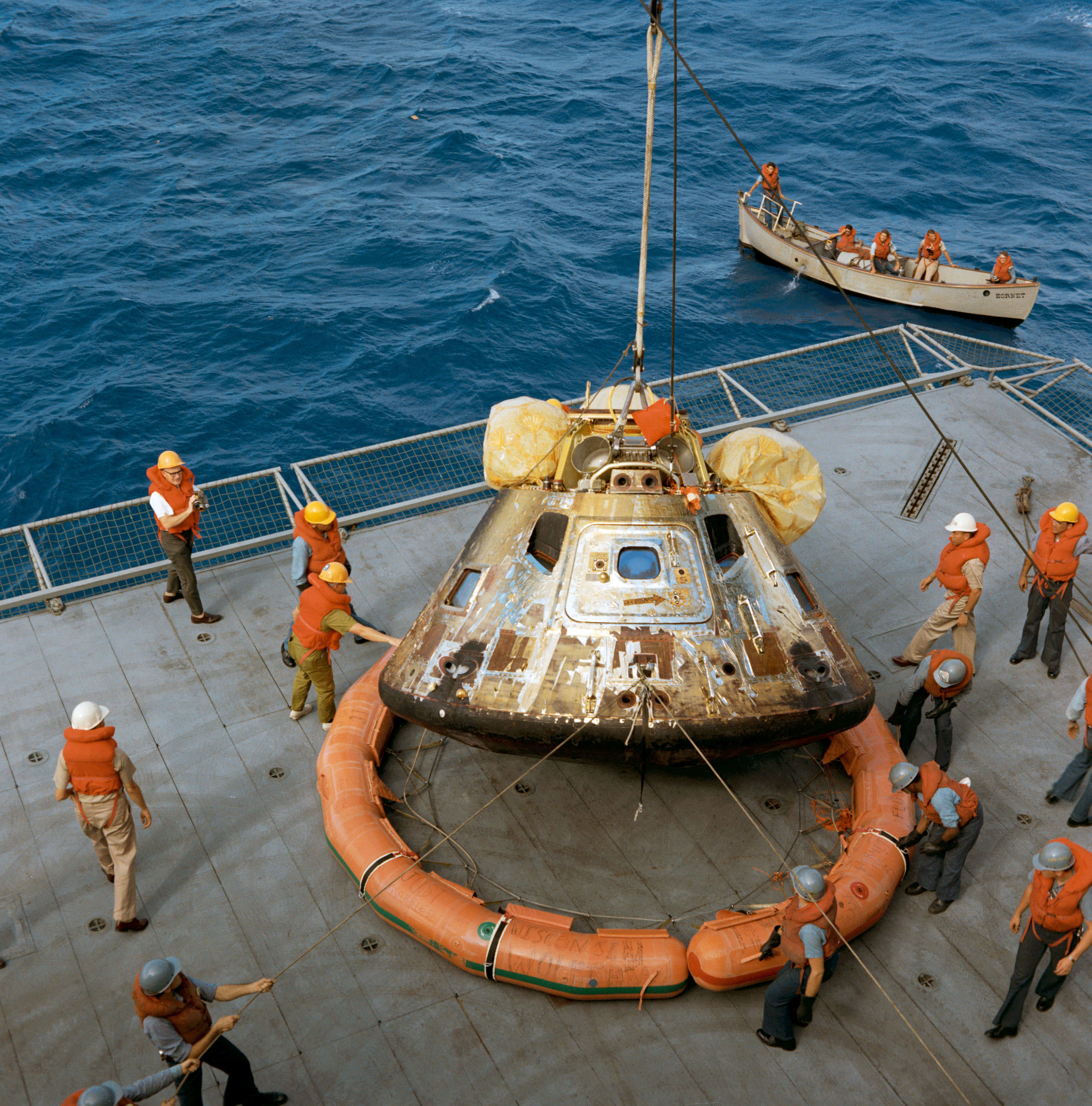 Workers pull the Apollo space capsule out of the ocean after splashdown 