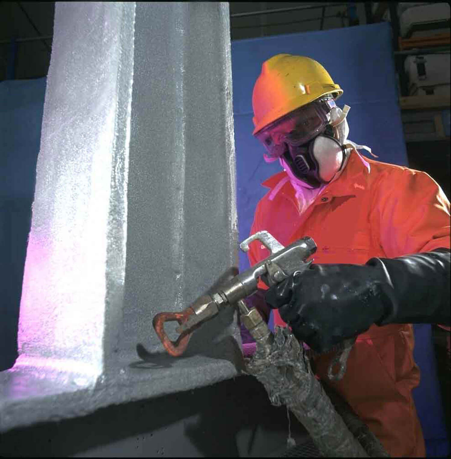 Worker applying fire-resistant reinforcement to metal beam 