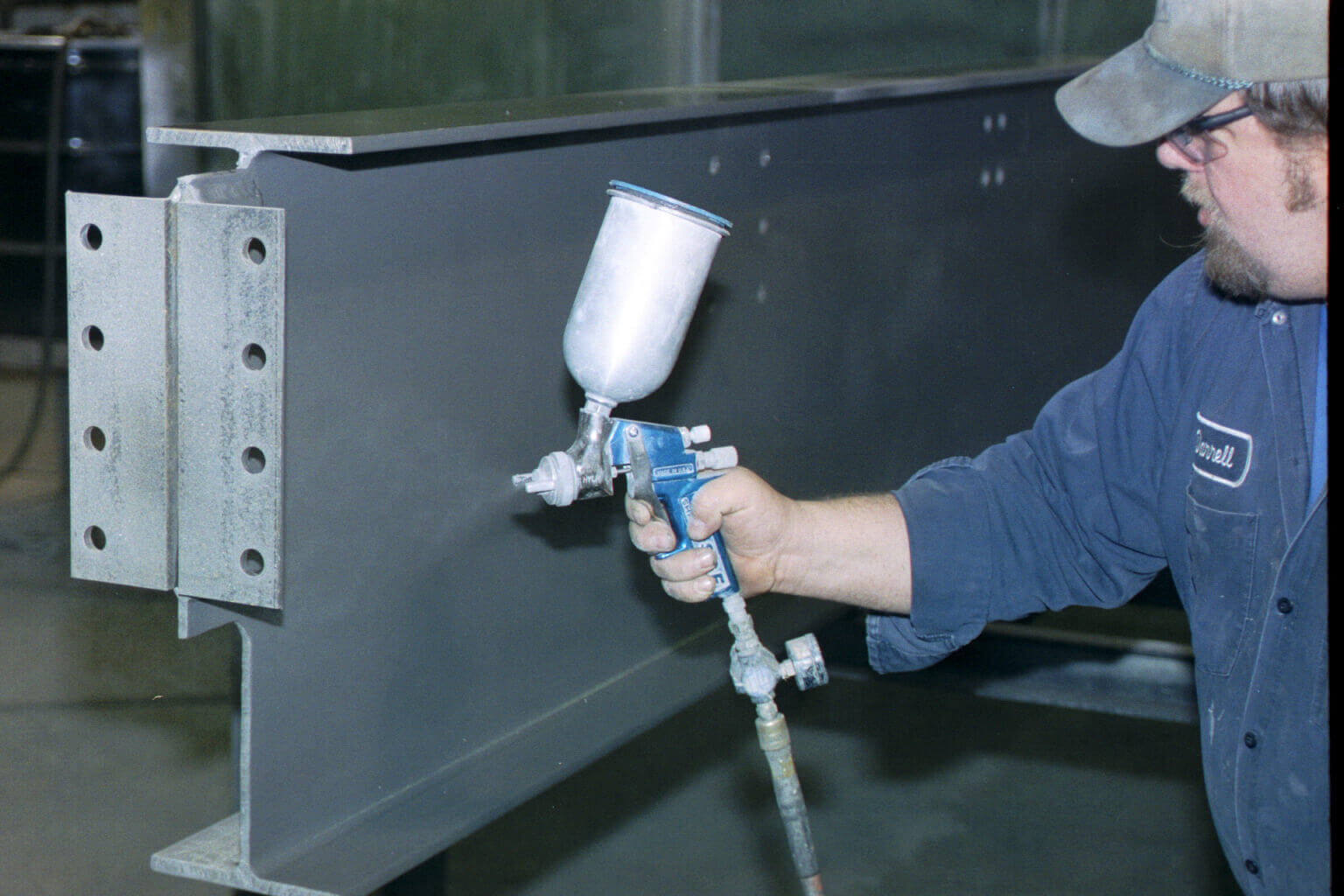 Man applying flame retardant material to metal beam 