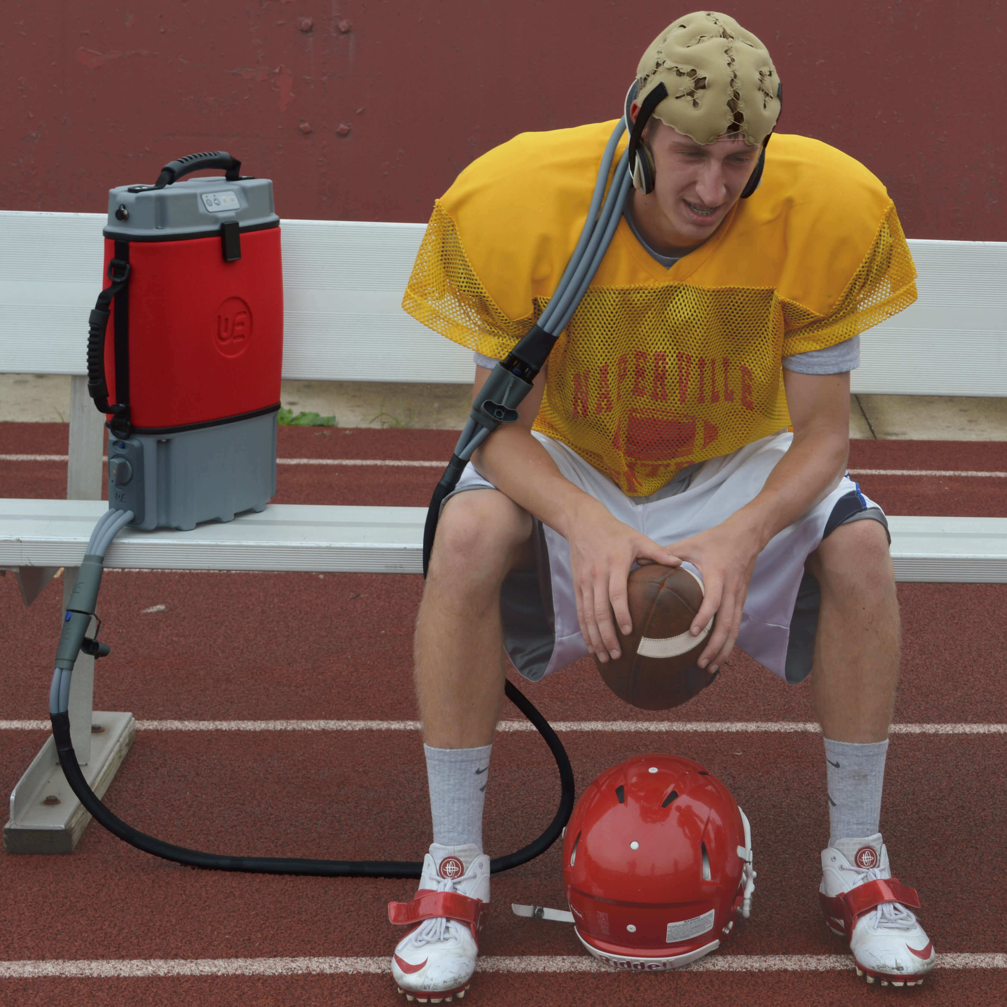 A football player uses a head-cooling device on the sideline 