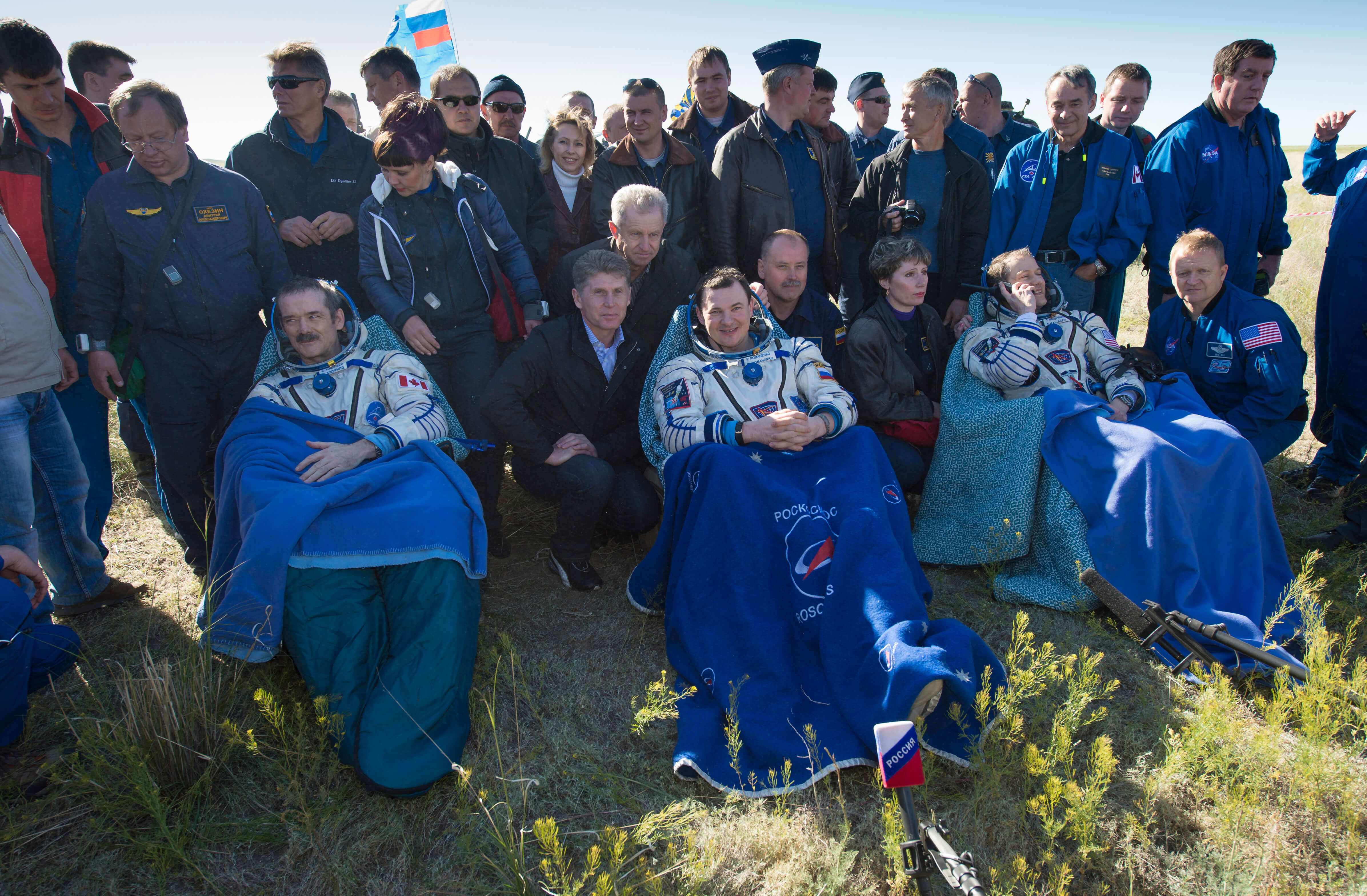 Astronauts sit in chairs after landing 