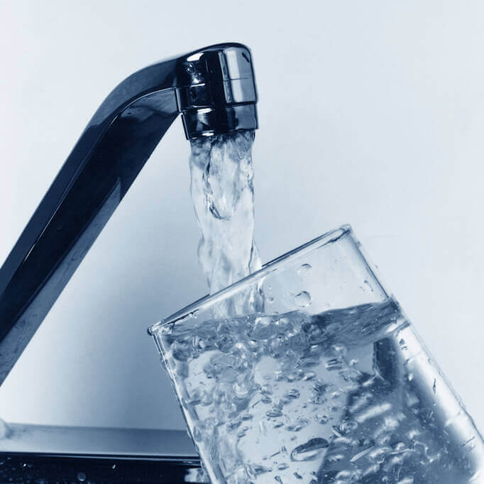 Water glass being filled from a sink faucet