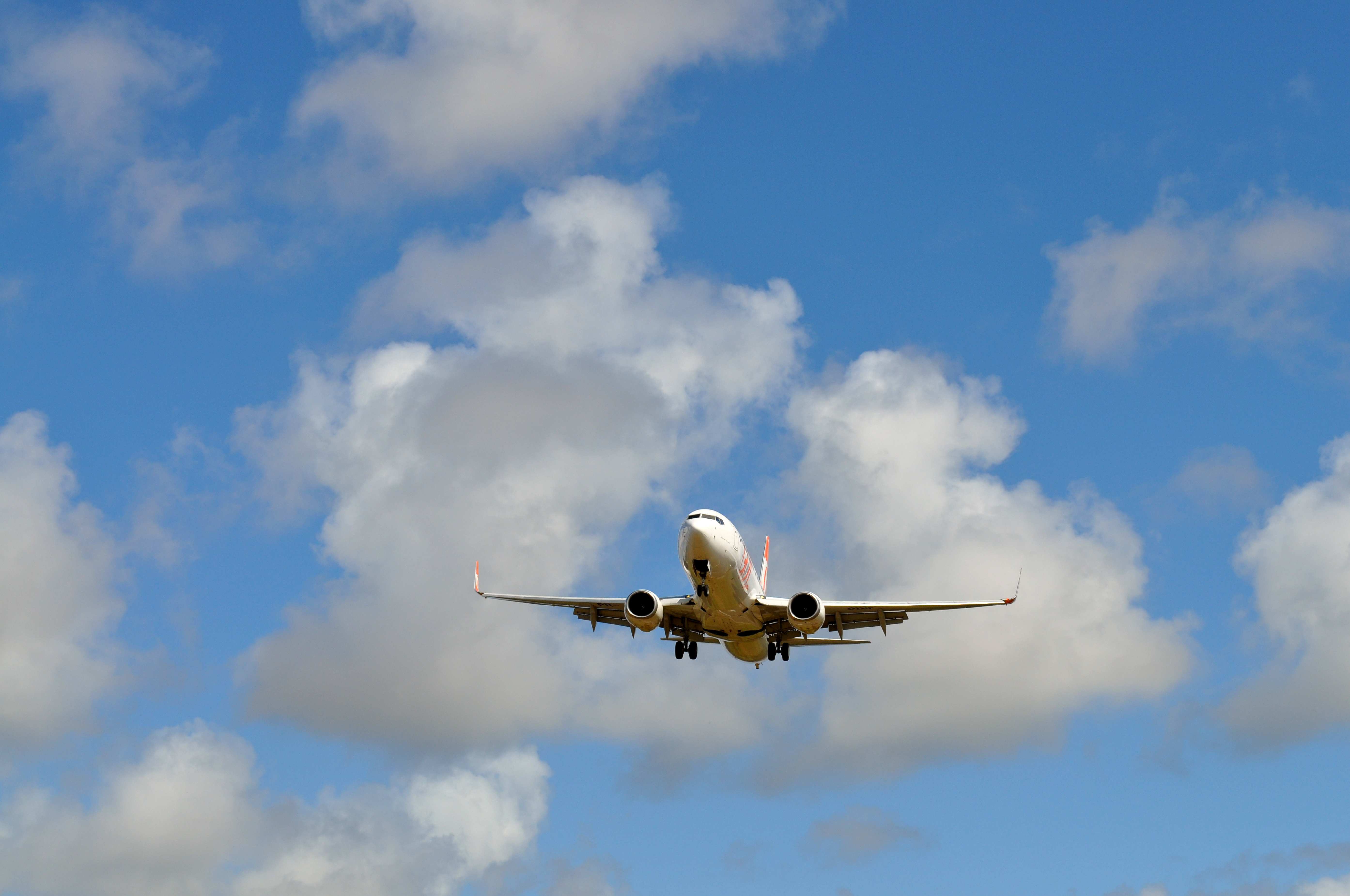 An airplane flying in a blue sky with clouds.