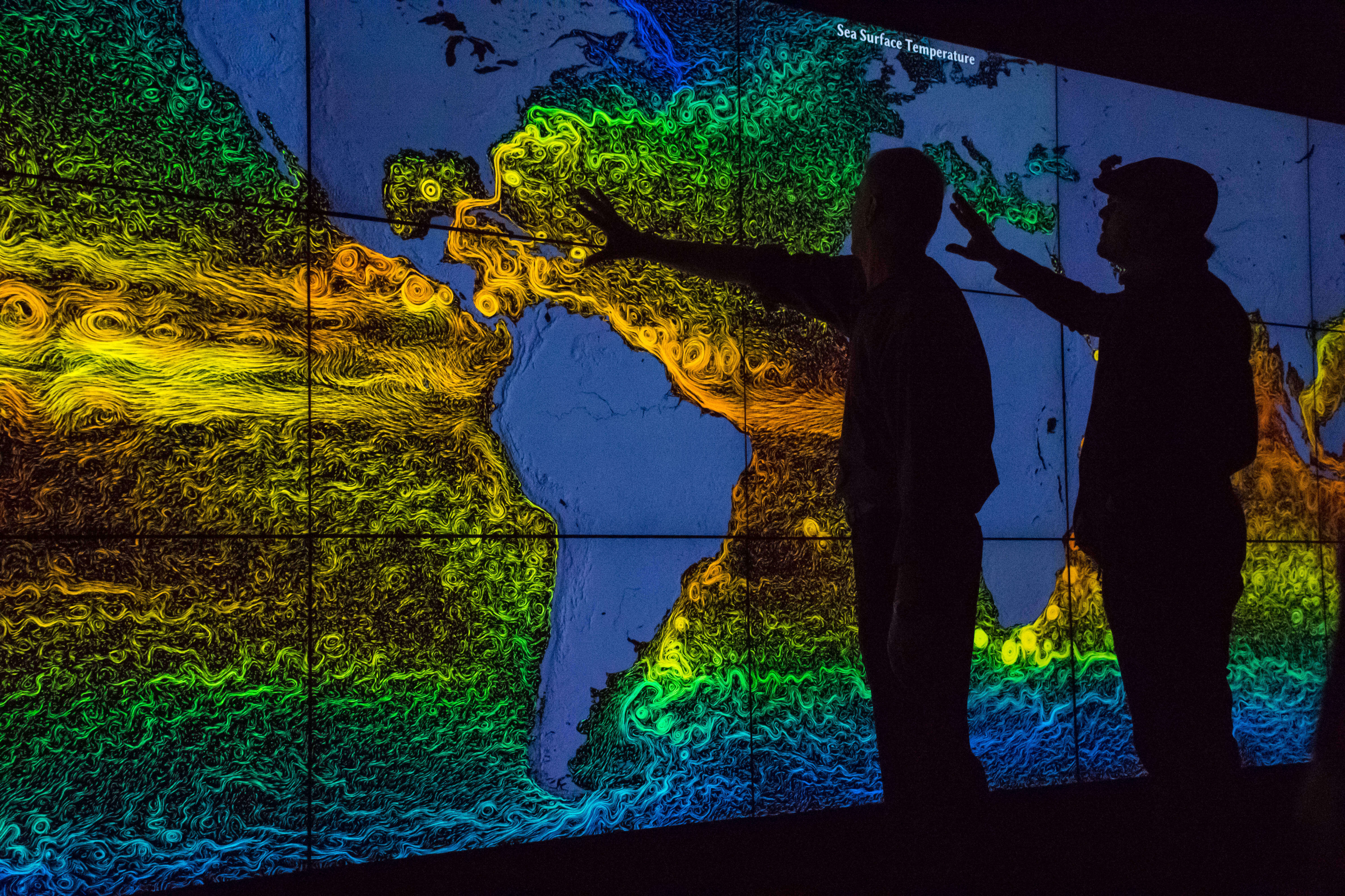Two people looking at a display of NASA ocean data