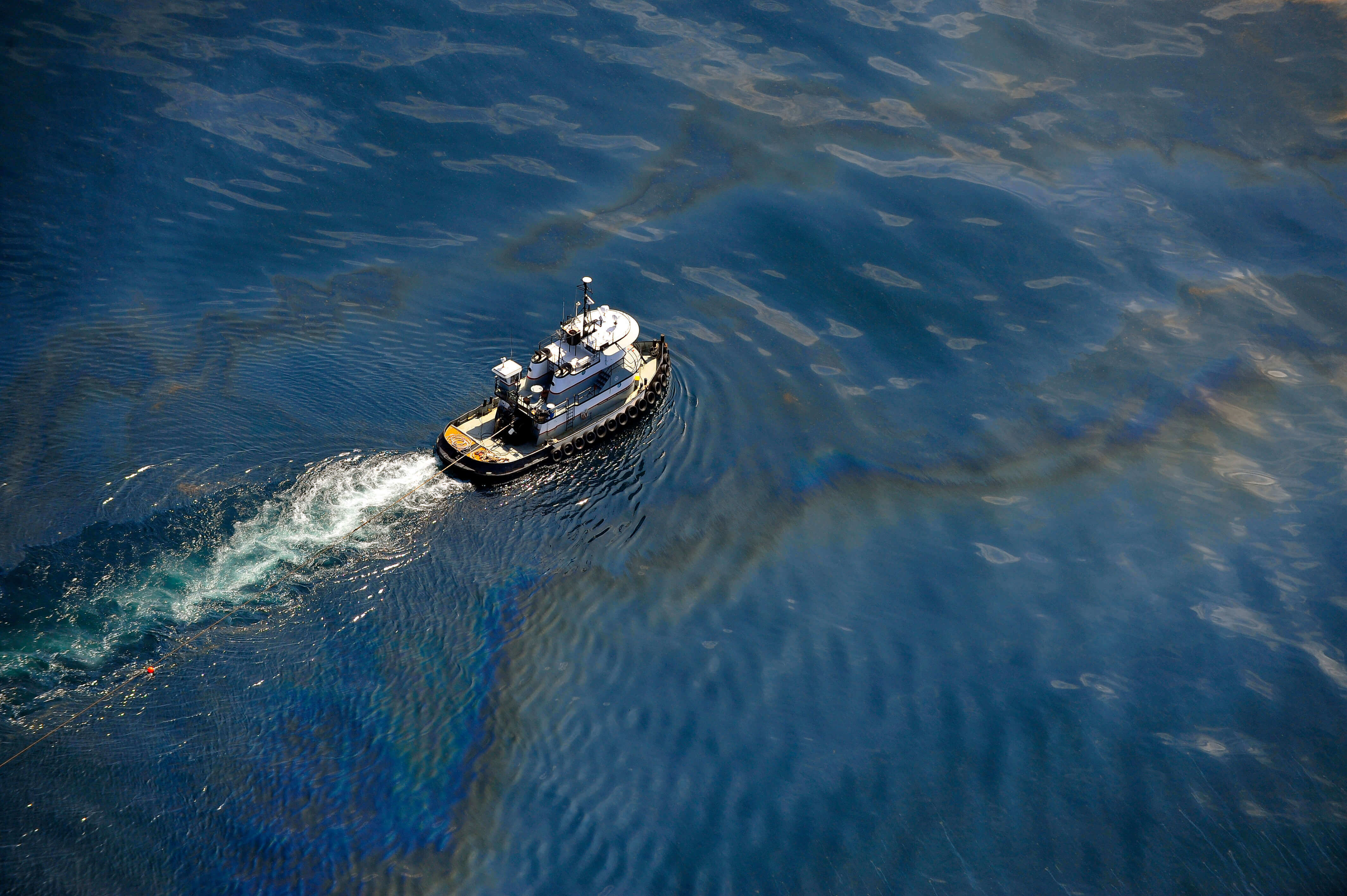 Tug boat sailing over an oil slick in the ocean