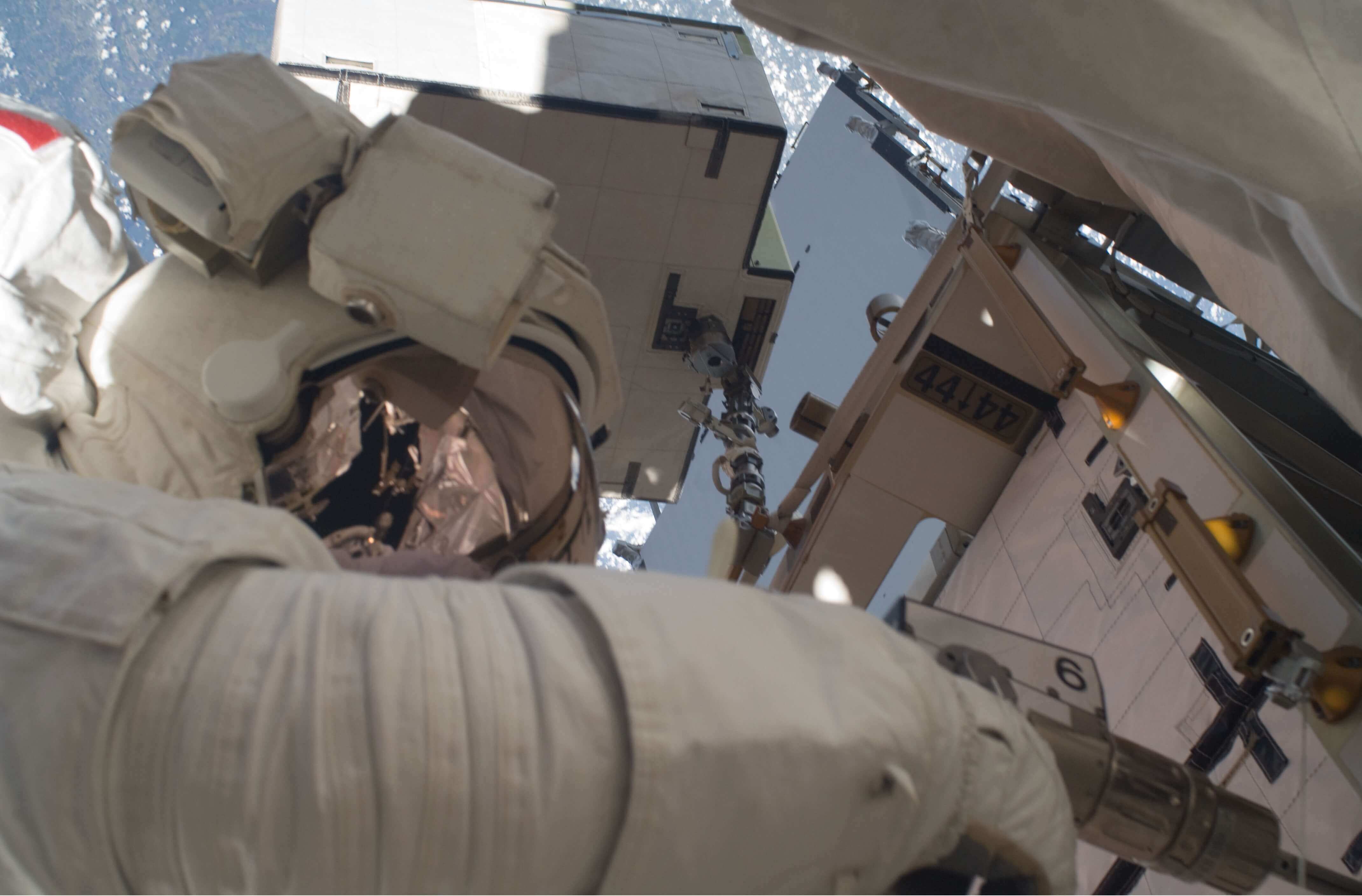 Astronaut working with a power tool on the exterior of the International Space Station