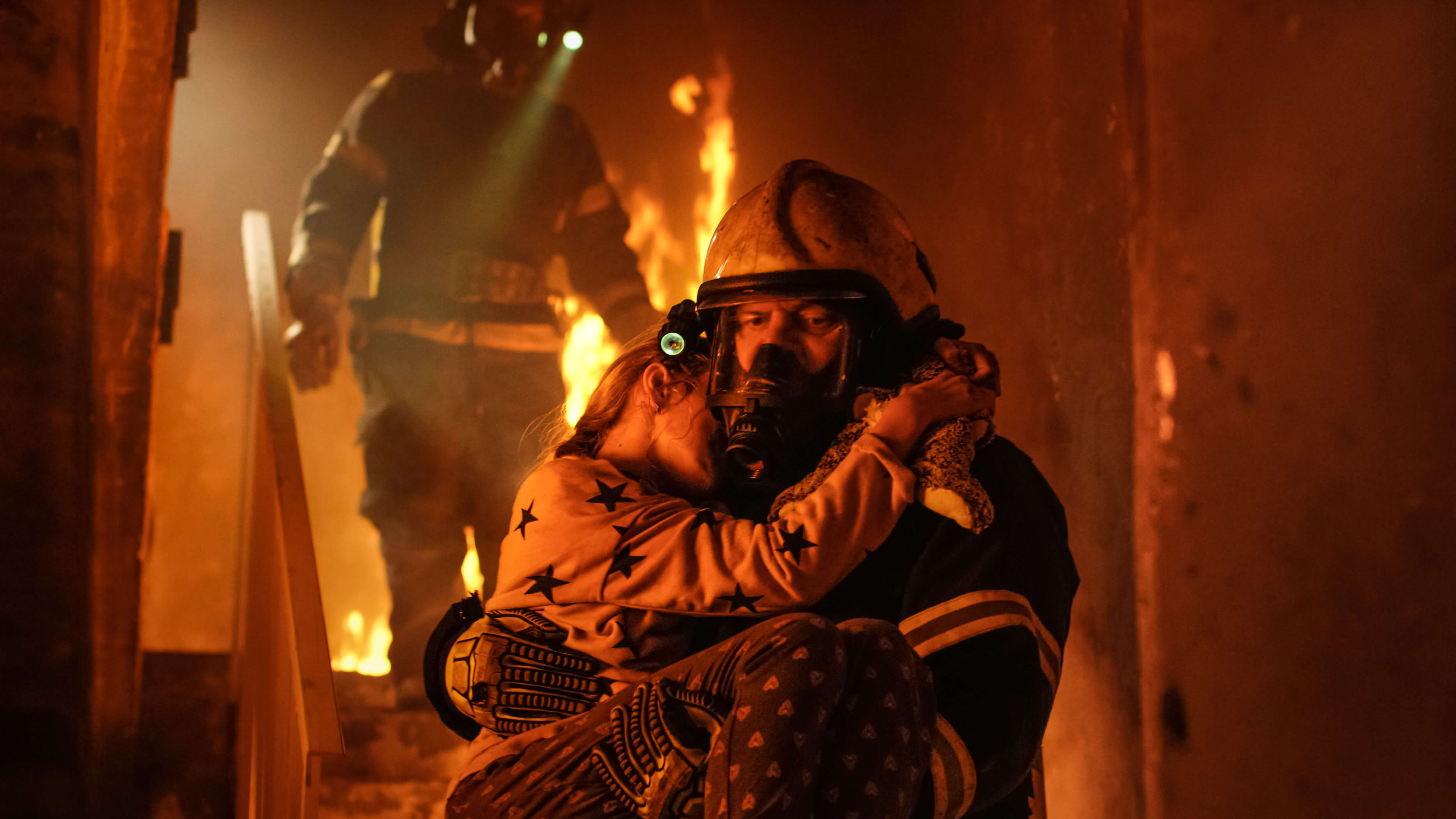 Firefighter carrying a girl from a burning building 