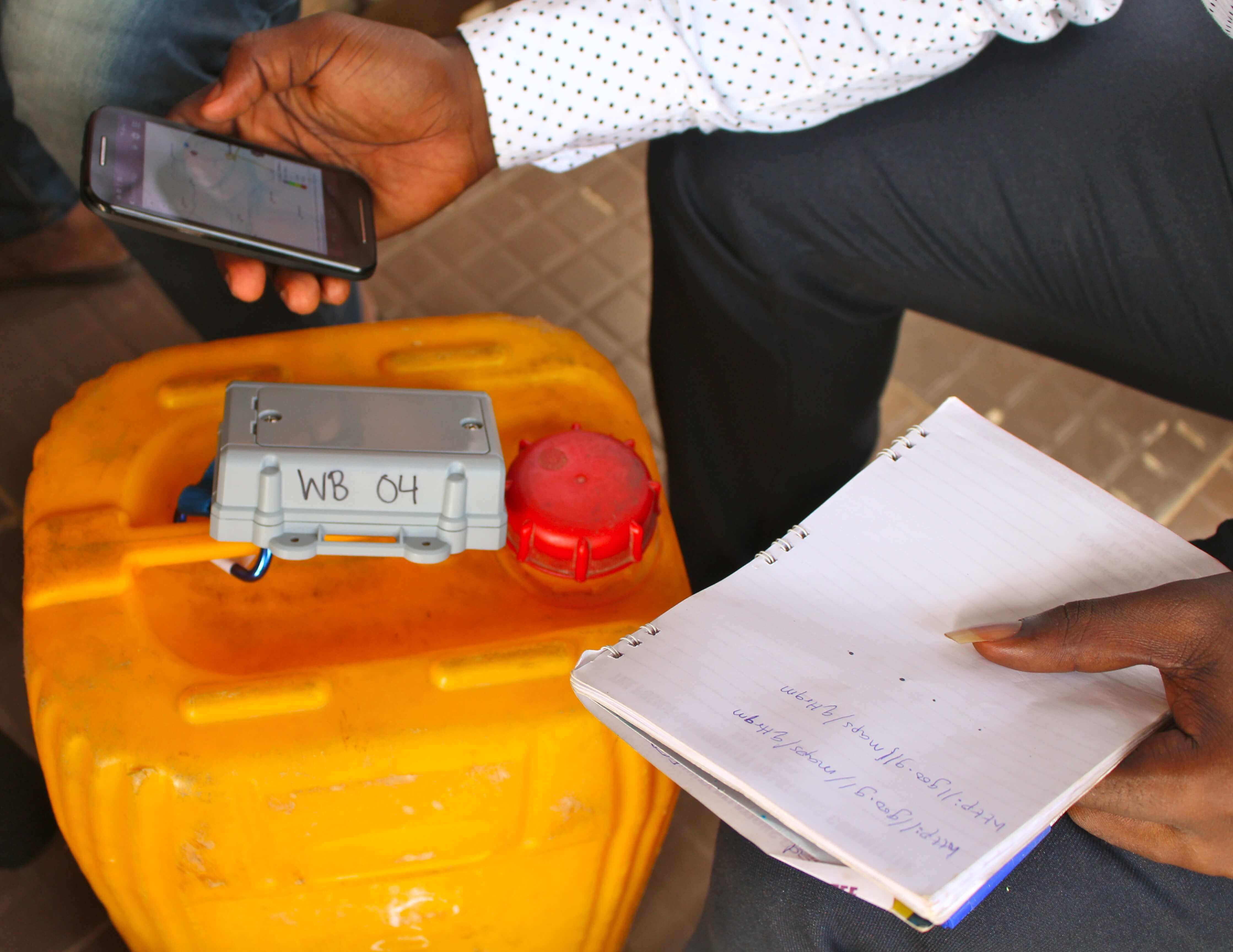 Hands holding smartphone and notebook over a water tank 
