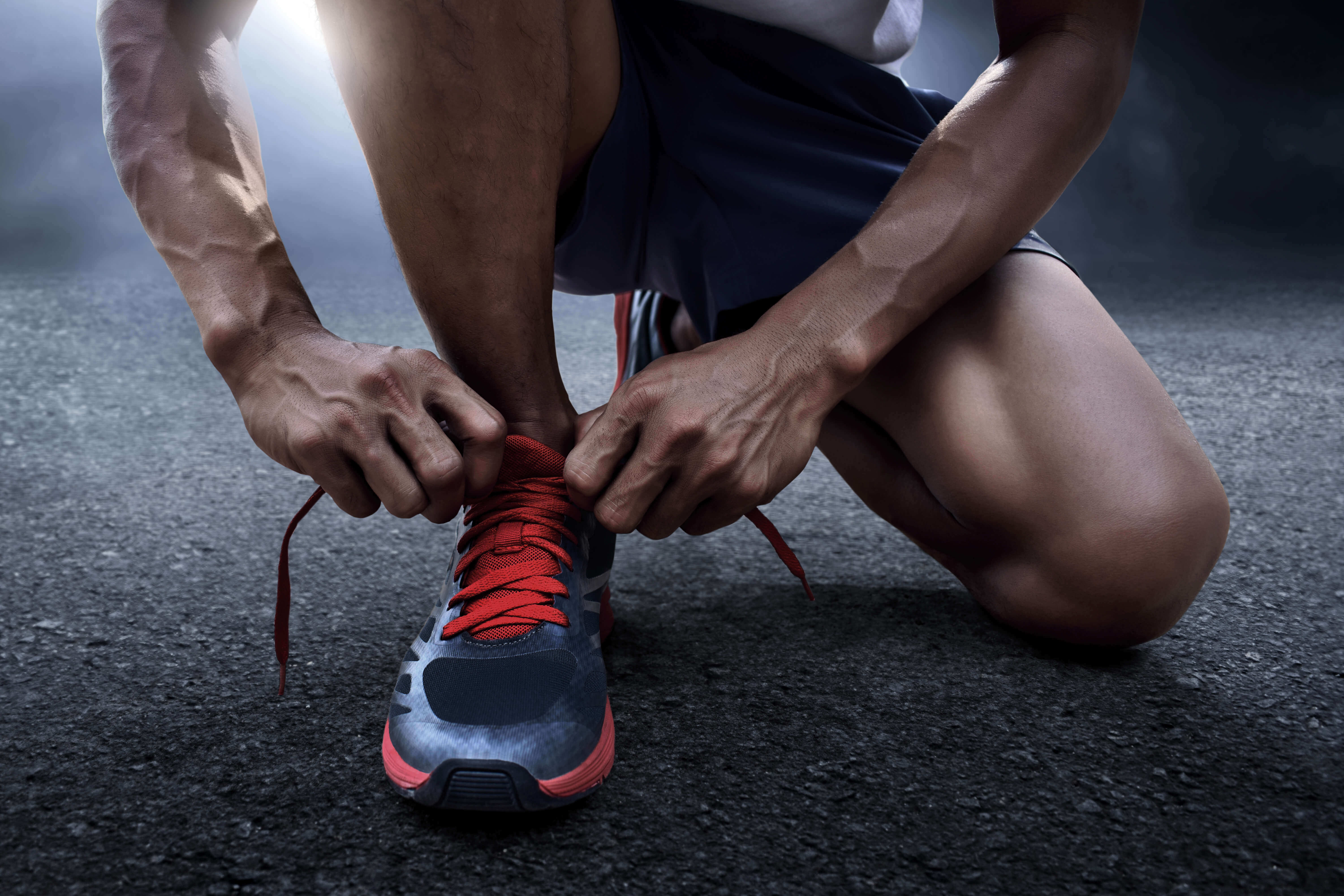 Man tying on an athletic shoe 