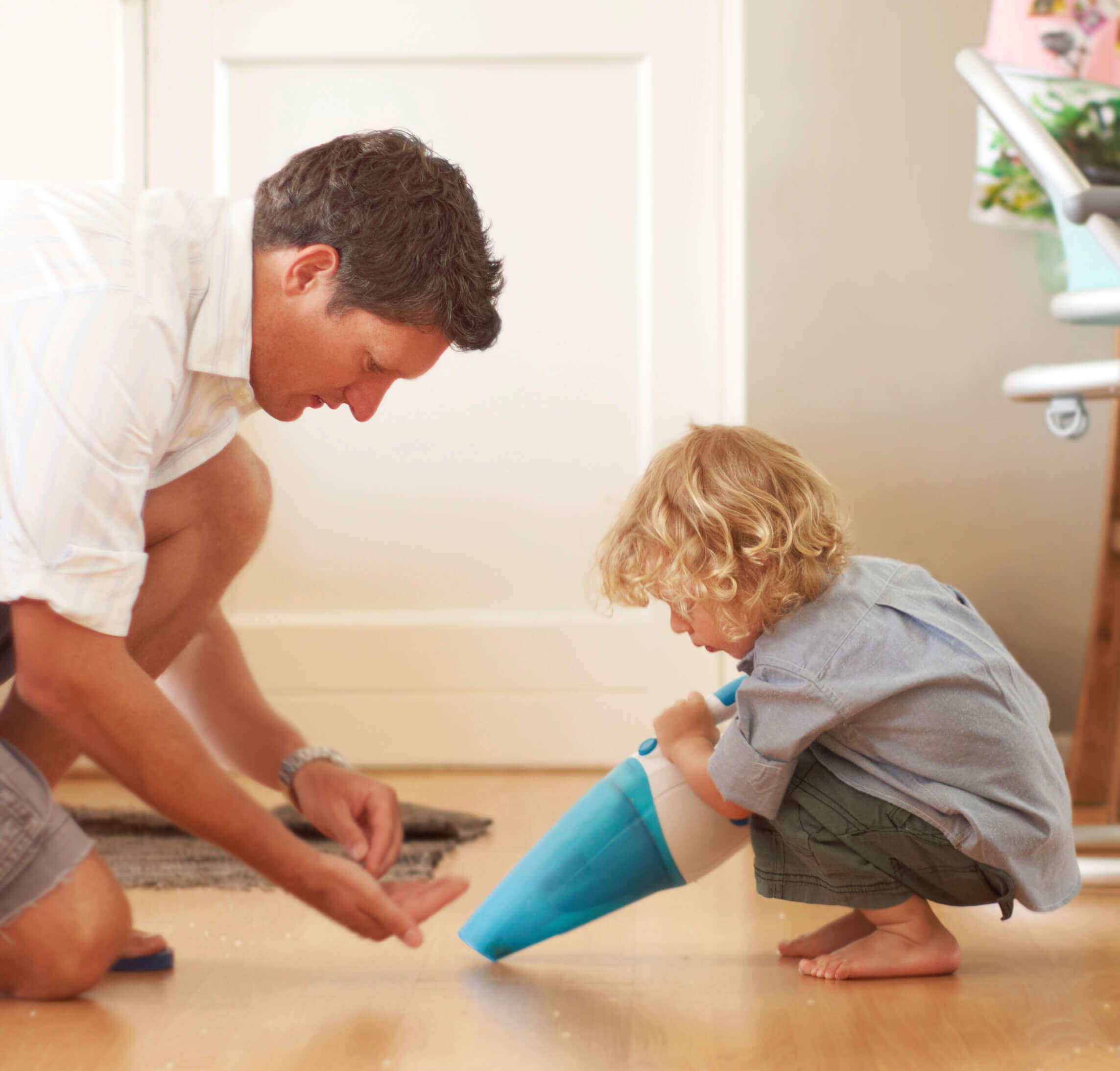 Father and son using a cordless handheld vacuum to clean up a mess