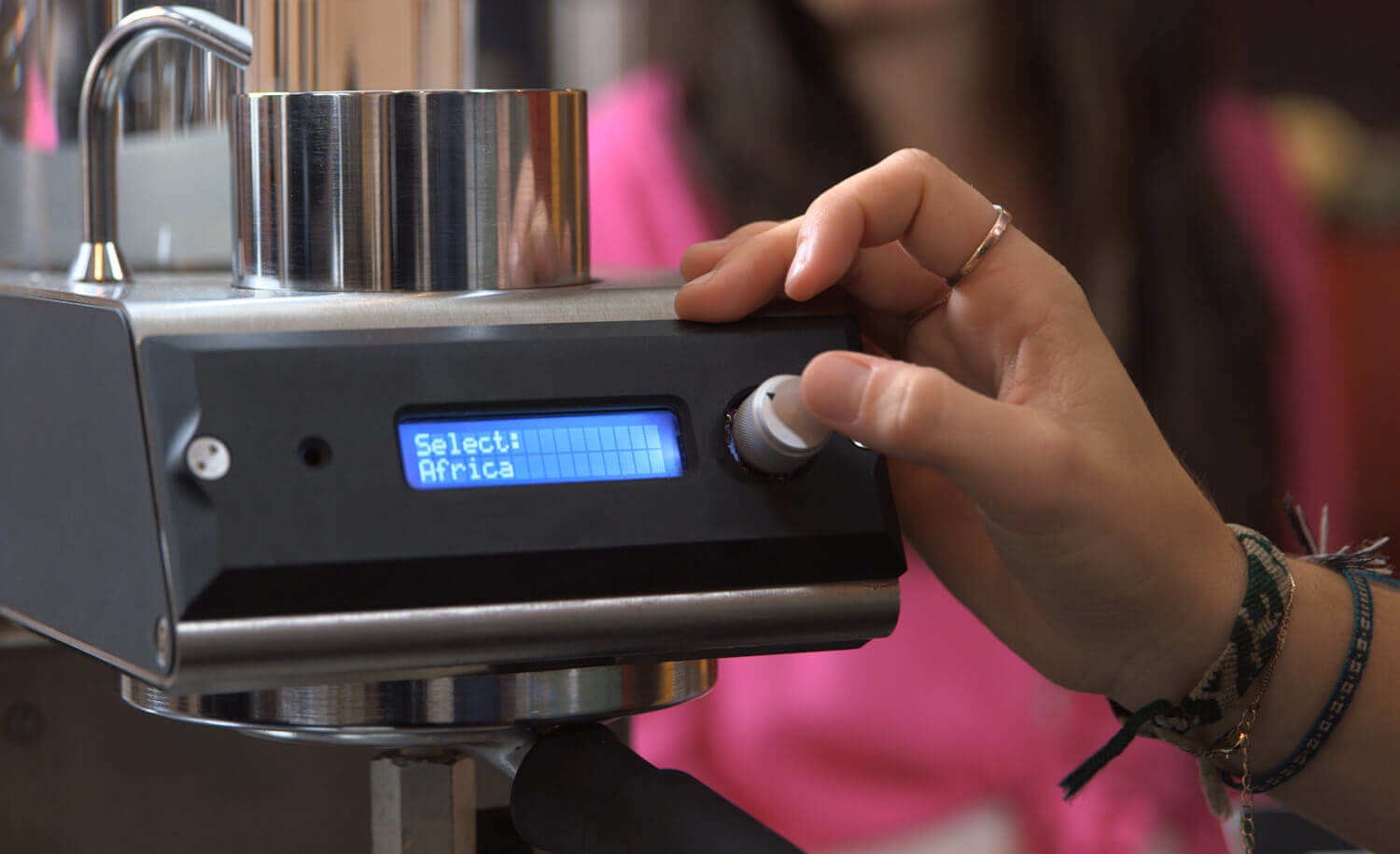 Barista adjusting settings on a precision coffee maker that incorporates NASA technology