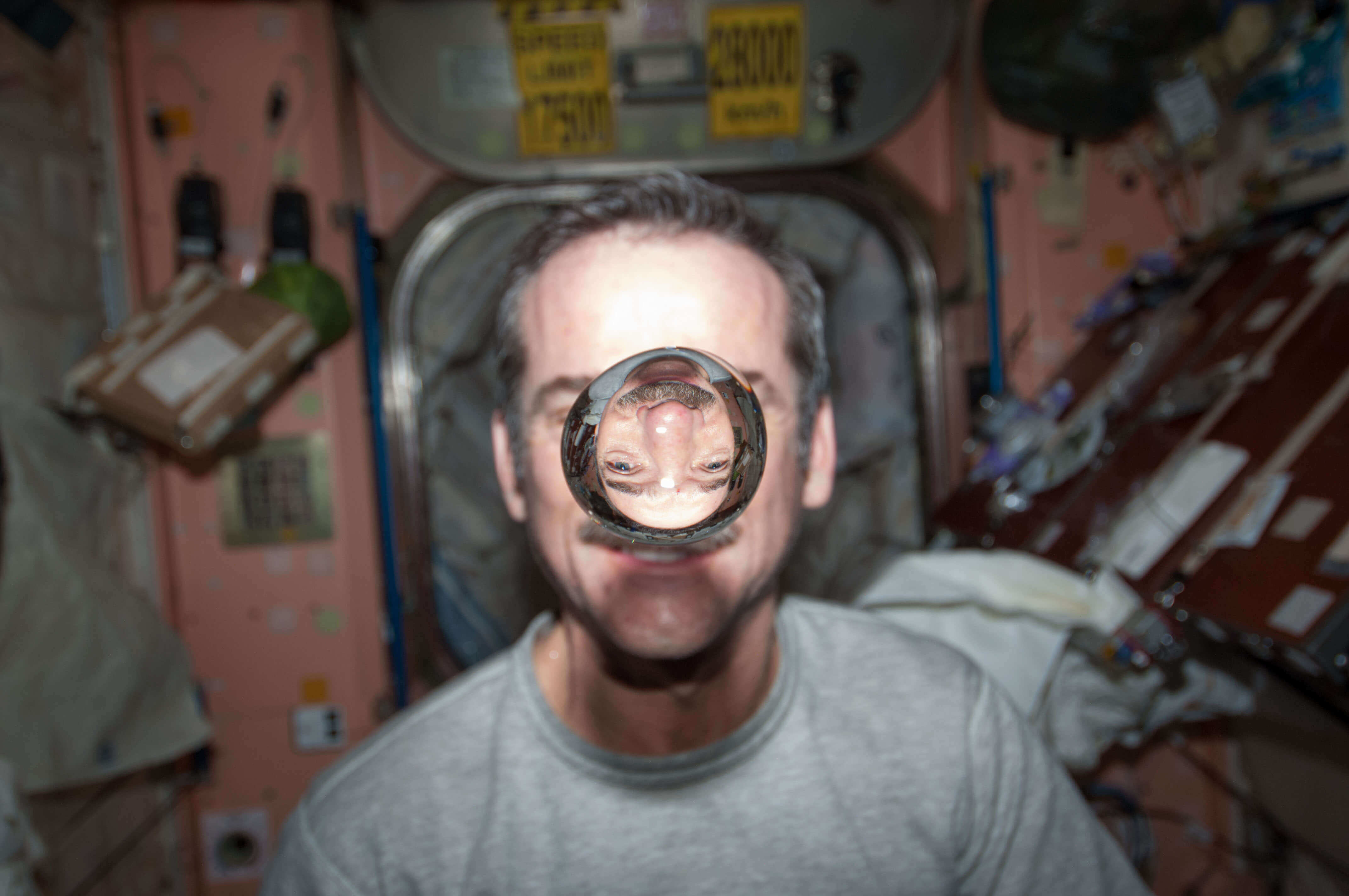 Canadian astronaut Chris Hadfield with a sphere of water floating in front of him on the International Space Station