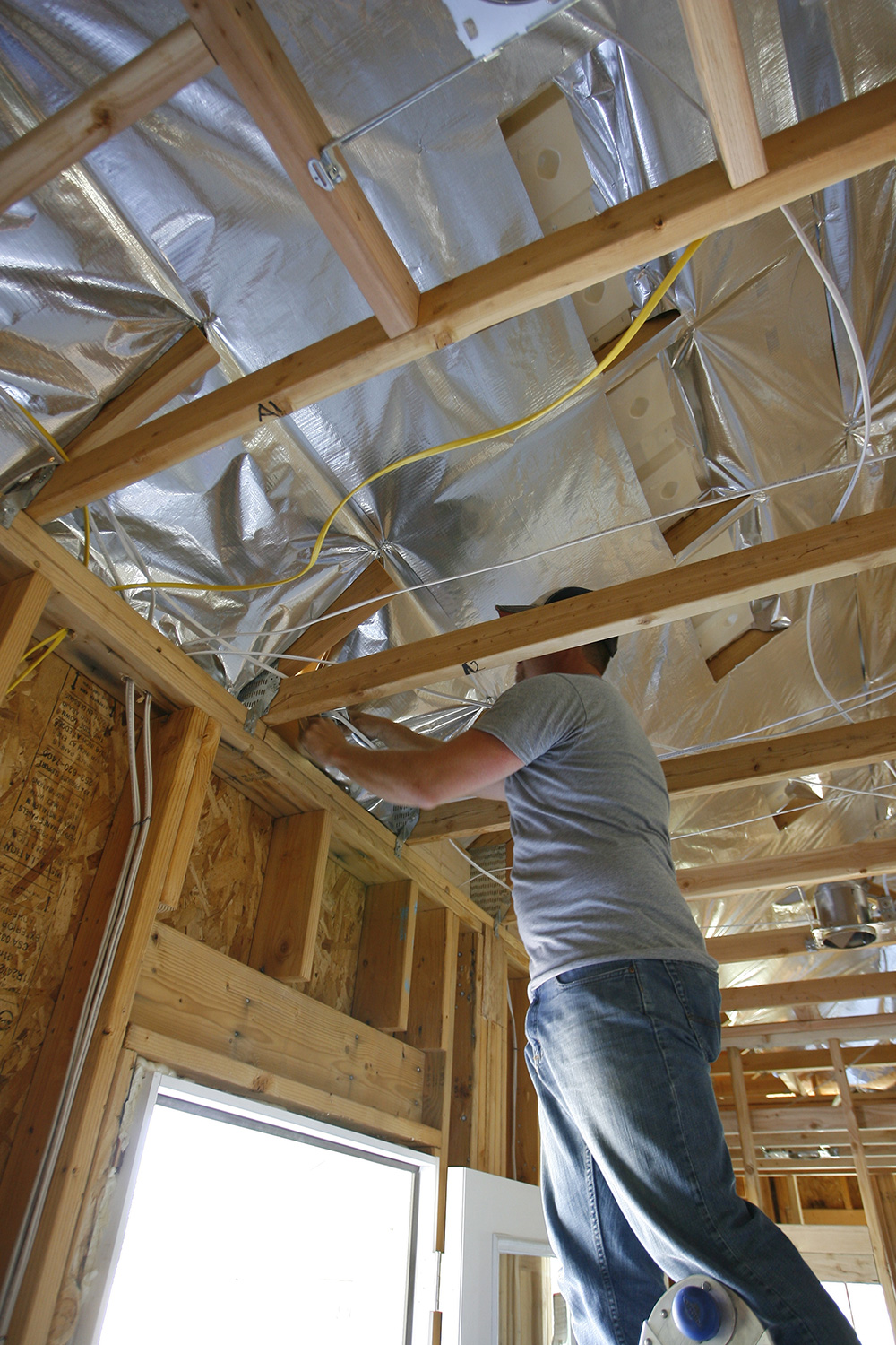 Man installing reflective insulation under house roof 
